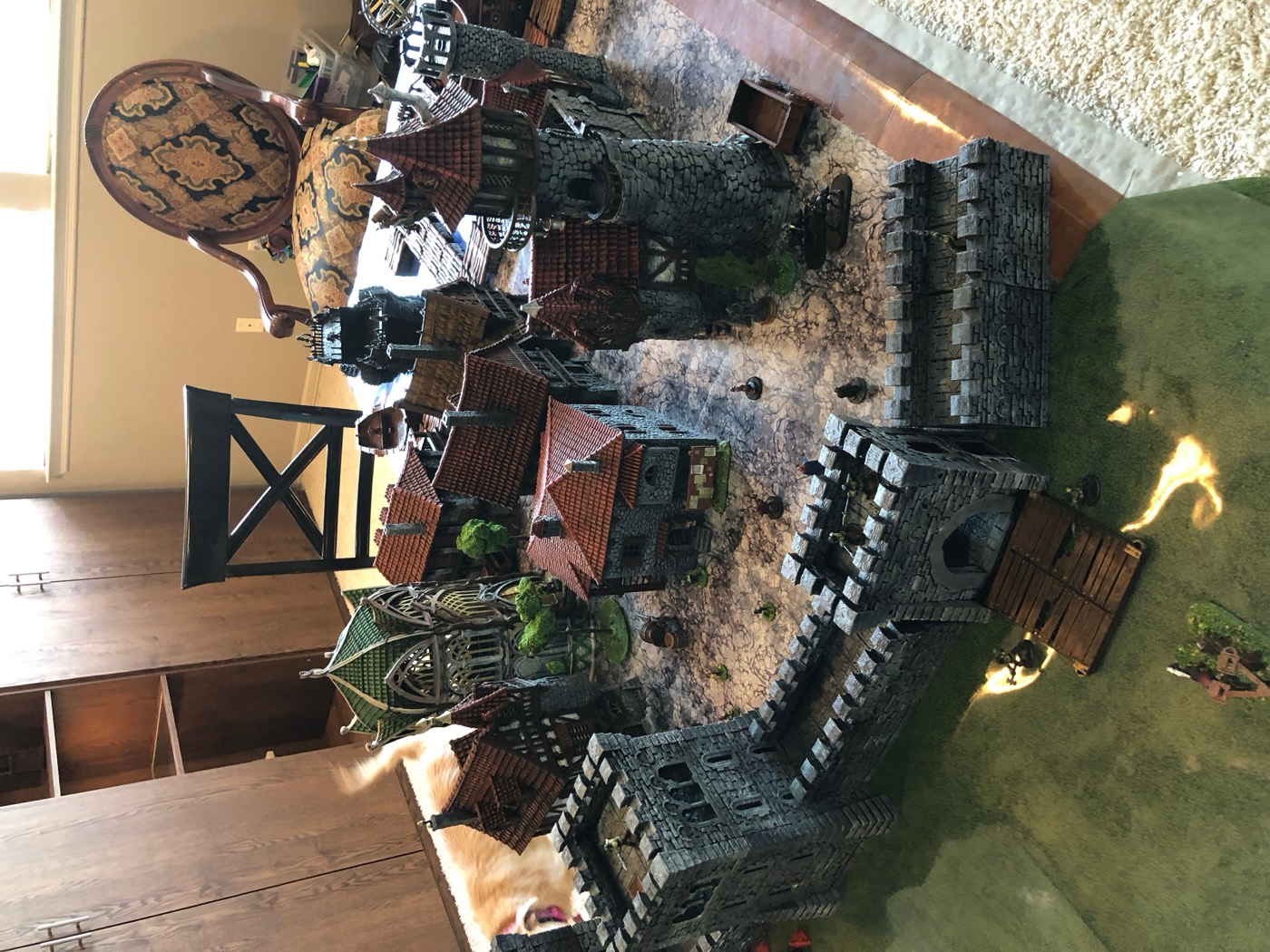 Painted stone walls with a town of timber houses and a tower behind them.