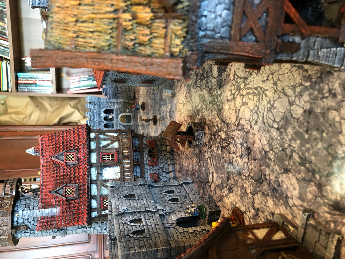 A town of painted terrain laid out on cobblestone tiles, seen from above with miniatures placed for a game.